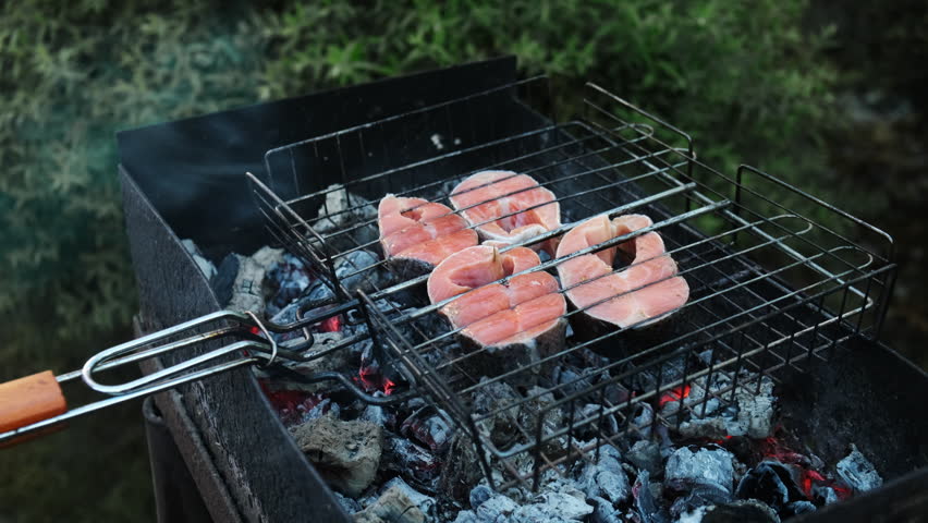 Grilling steaks of salmon fish outdoors. Summer weekend activity, barbecue, cookout, picnic