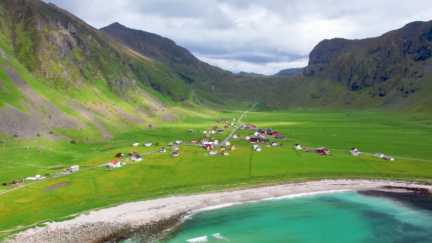 Aerial drone view of Lofoten Islands in Norway, featuring beautiful landscapes on Unstad Beach, white sand, clear water and dramatic mountains near the shore. Experience the natural beauty
