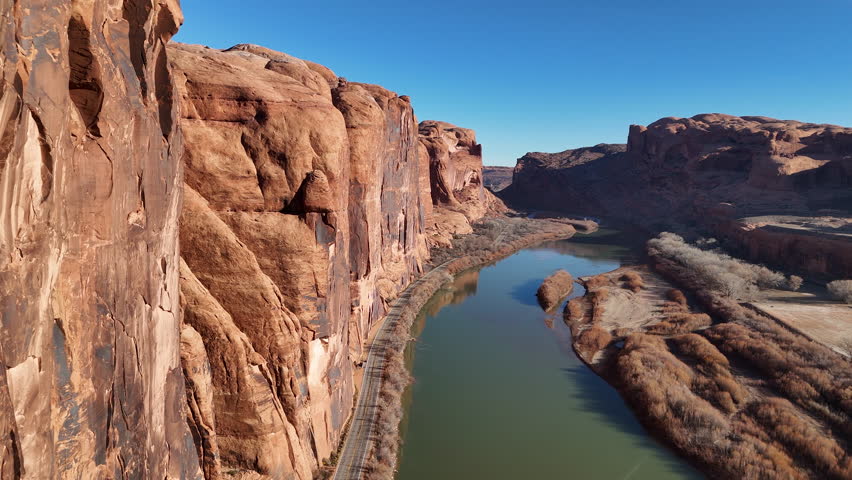 Drone Shot of Majestic Red Sandstone Cliffs Above Road and Colorado River Near Moab Utah USA