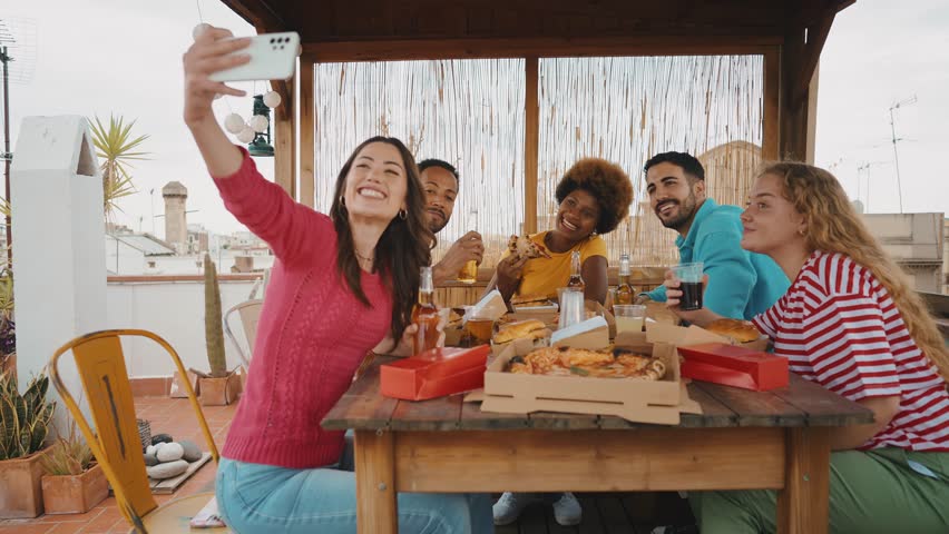Multiethnic group of friends having dinner barbecue party on rooftop at home