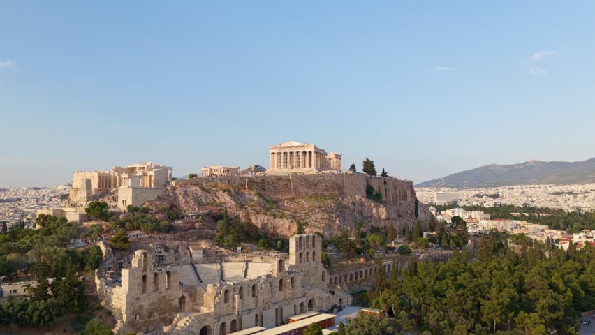 Amazing aerial shot slowly revealing the ancient acropolis of athens, with the parthenon temple and the odeon of herodes atticus, showing the entire cityscape during a sunny day in greece