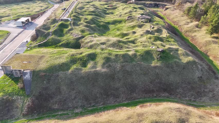 Aerial top-down view of grassy shell craters, paths, and preserved fortifications at Fort de Vaux near Verdun, France.