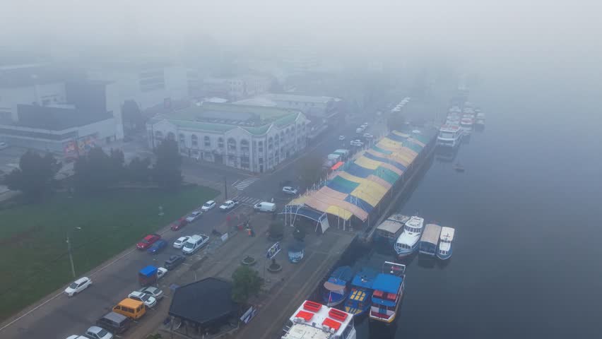 Aerial orbit over the river fair in Valdivia, Chile, with its colorful roof and tourist boats along the banks of the Calle Calle River
