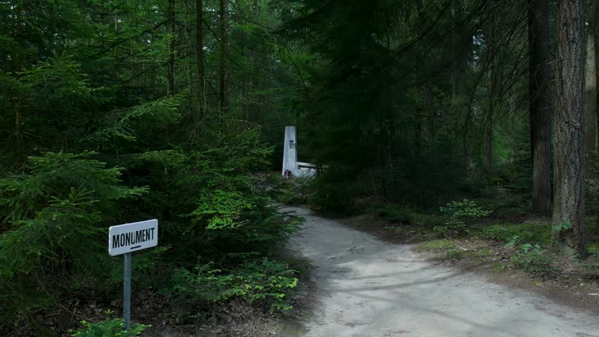 Monument sign pointing to a memorial stone deep in a forest