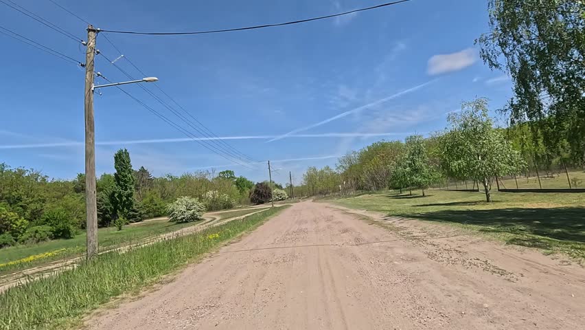 A picturesque journey along a country road to the forest under a clear blue sky