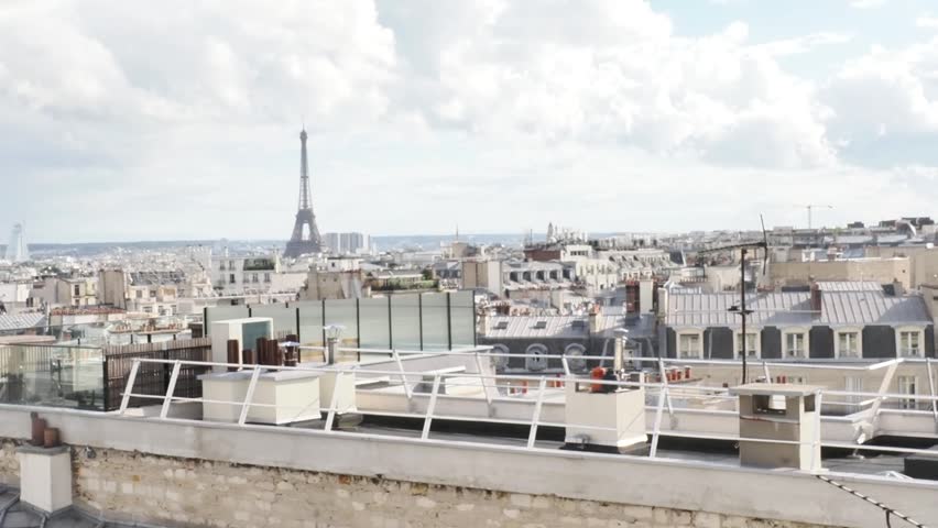 Panoramic rooftop view over Paris featuring the Eiffel Tower under dramatic clouds, filmed during an outdoor corporate event in the French capital.