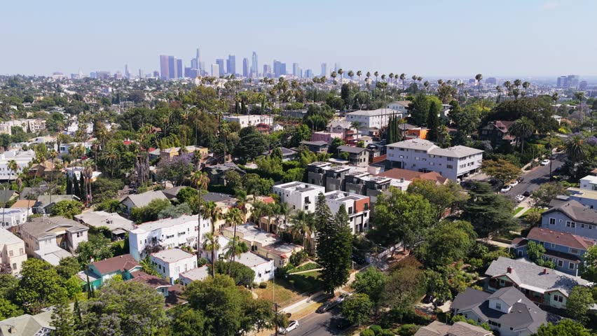 Expansive Los Angeles cityscape displaying suburban houses and downtown skyscrapers, residential neighborhood greenery and urban architecture