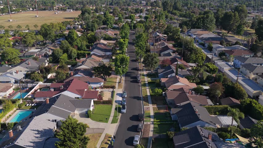 Aerial survey over Los Angeles, California showing houses with swimming pools, residential buildings, parked cars from a tripod elevated perspective