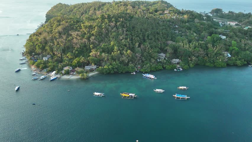 Drone shot of island boats near a forested Puerto Galera shoreline