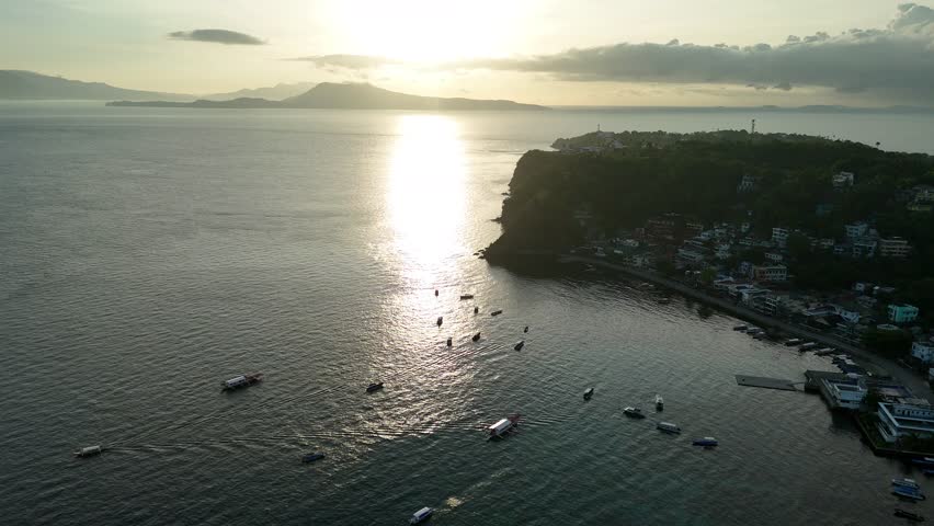 Golden sunset aerial over Sabang Puerto Galera with boats across tropical bay
