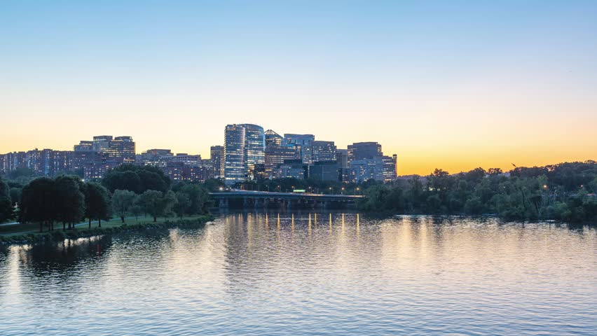 Arlington, Virginia, scenic static 4K timelapse video capturing the transitioning gradient sky over the illuminated Rosslyn skyline as office lights flicker and ripples move across the Potomac River at sunset.