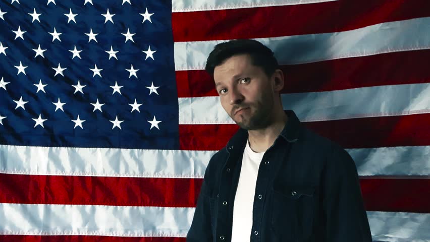 American man standing proud in front of a flag of the United States and holding a sign celebrating the America 250 semiquincentennial