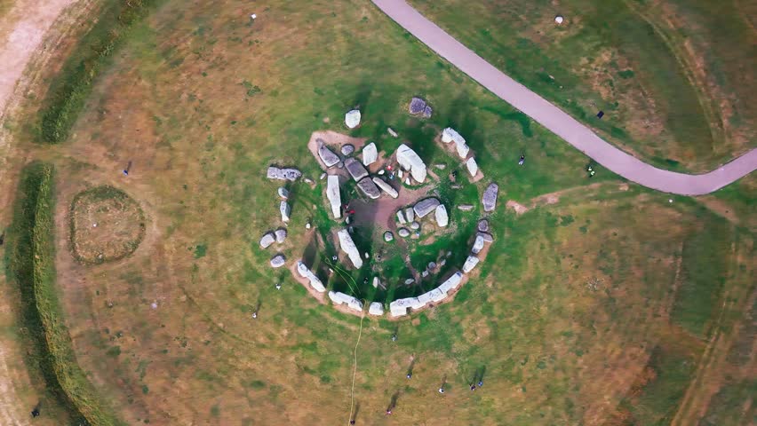 Top down drone aerial view of Stonehenge, showing the ancient prehistoric stone circle, surrounding grassland, visitor paths and people in Wiltshire, England.