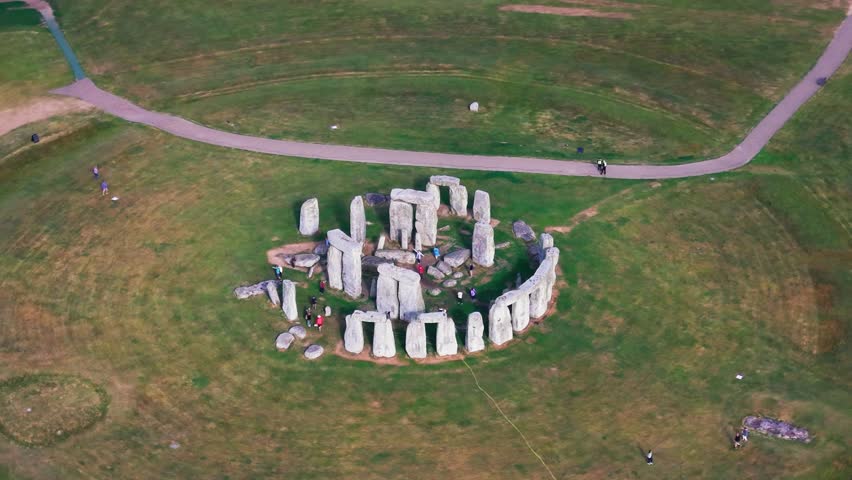 Drone aerial view of Stonehenge, the ancient prehistoric stone circle surrounded by grassland, paths and visitors in Wiltshire, England.