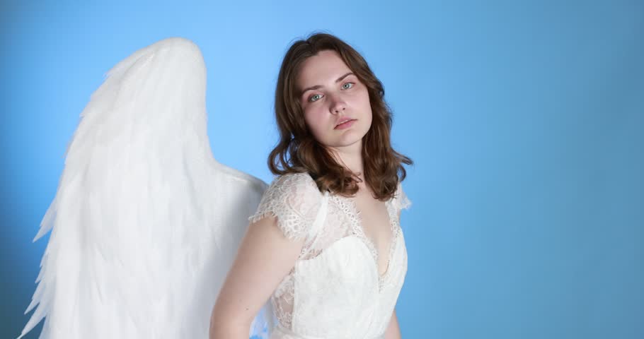 Beautiful girl with angel wings on light blue background, camera moving out