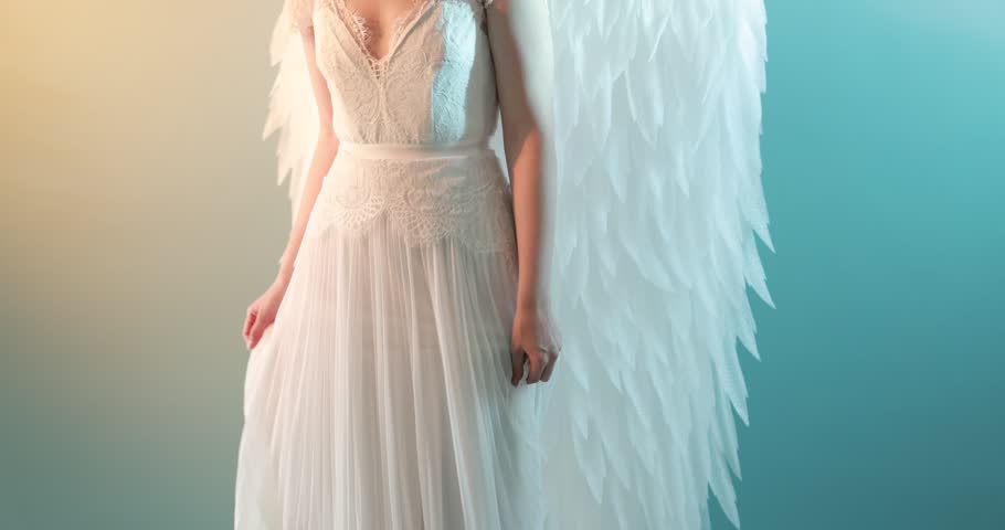 Beautiful girl dressed as angel in neon light on color background, camera moving up