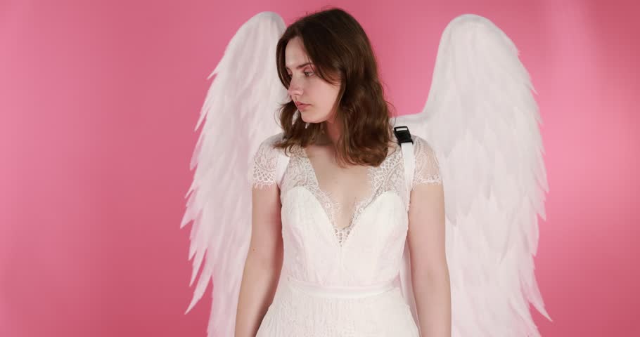 Beautiful girl with angel wings on pink background, camera moving in