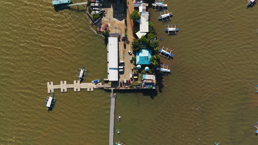 Fishing vessels and seaside pier seen from above in warm Palawan waterscape bay