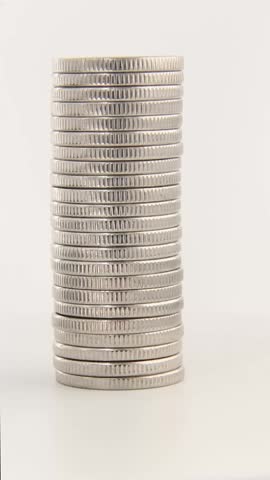 A high vertical stack of silver coins stands on a clean white background as the tower gently turns and shifts slightly, emphasizing wealth preservation, savings goals and financial security.