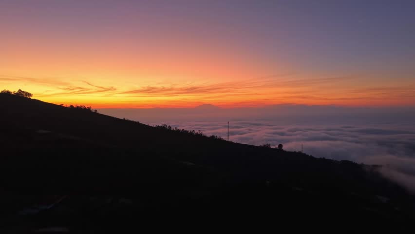 Golden dawn sky above misty clouds and mountain terrain. Peaceful sunrise scene featuring dramatic natural beauty and scenic horizons.