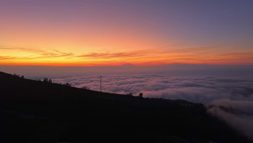 Aerial view of a mountain hillside at sunrise above the clouds. Stunning dawn colors, natural beauty, and serene outdoor scenery.