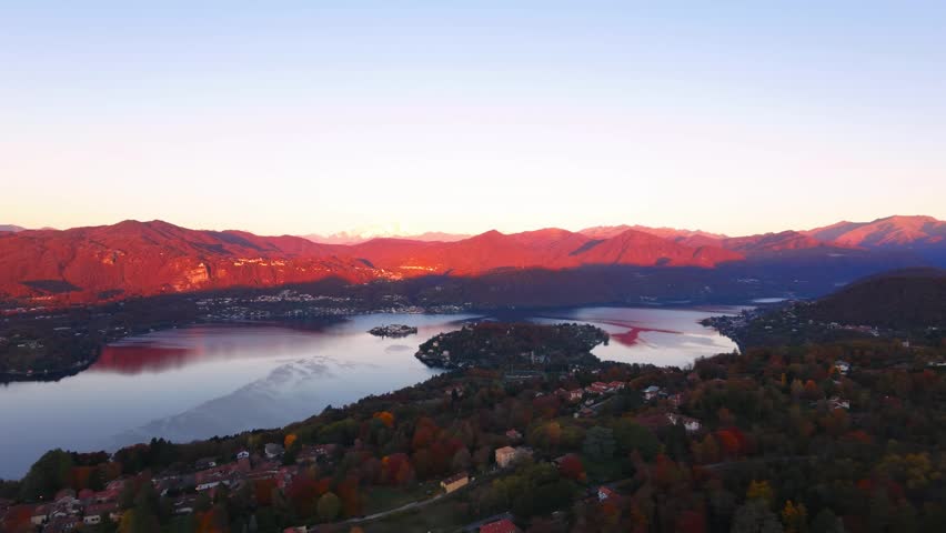 Lake Orta and Isola San Giulio surrounded by mountains at sunset in Piedmont, Italy. Aerial drone panoramic view, landscape, copy space
