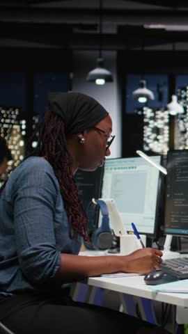 Vertical video Technician writing down automation ideas on paper to streamline repetitive tasks using AI scripts. IT expert documents artificial intelligence strategy on notepad to speed up