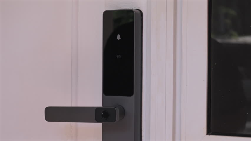 A close up video of a person tapping an RFID key fob onto a modern black smart lock to open a door.