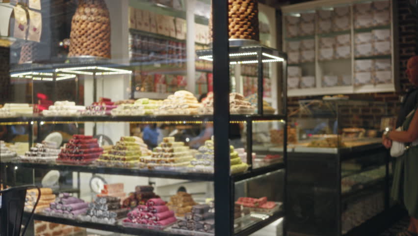Blurred shop window display of colorful turkish confections on glass shelves and warm lights with shallow bokeh shop; background backdrop copyspace.