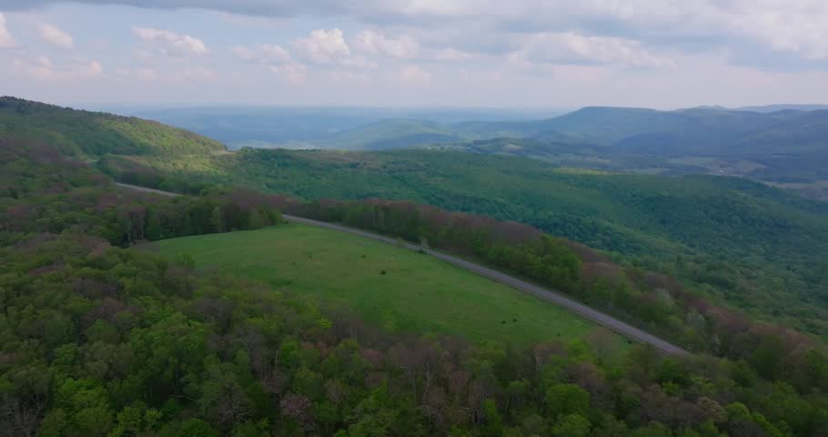 Forested mountain landscape and scenic roadway in West Virginia, aerial drone pullback to reveal grand background