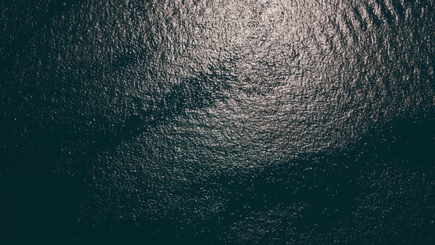 Deep, dark water surface with gentle ripples and a soft reflection of sunlight, creating a tranquil and mysterious natural texture background perfect for contemplative or moody concepts