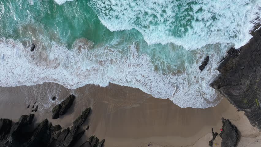 Waves crash against the rocky shoreline, creating dynamic patterns at Coumeenoole Beach. Ideal for ocean-themed projects or coastal scenery backdrops.