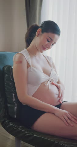Smiling pregnant woman showing her arm after receiving a vaccination.