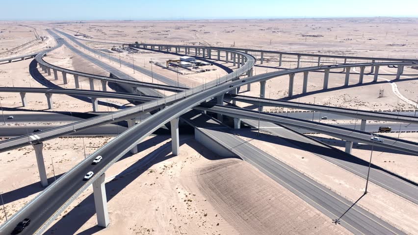 Drone view of multi level highway interchange spanning desert terrain, showcasing transportation infrastructure, engineering and connectivity in the Middle East