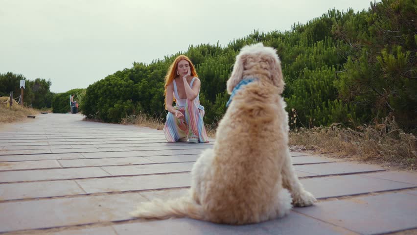 Red haired woman going out with doodle dog on boardwalk