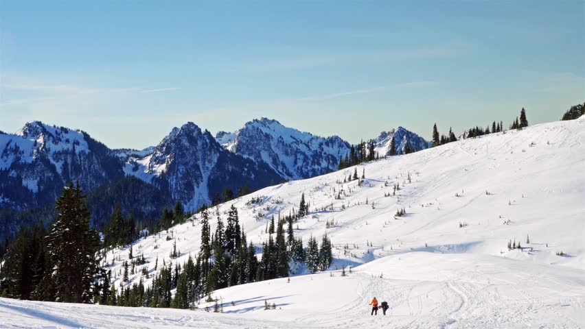 Scenic winter landscape footage of people snowshoeing on the snow-covered Skyline Trail towards Panorama Point in the Paradise area of Mount Rainier National Park, Washington State. The view features