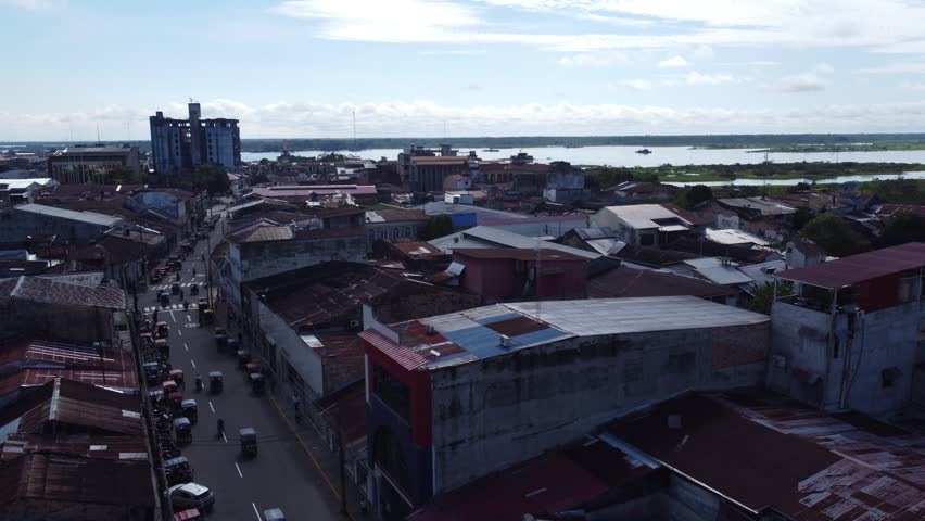 A serene aerial shot showcasing the urban layout and natural beauty of Iquitos, Peru, with a mix of modern and traditional architecture.