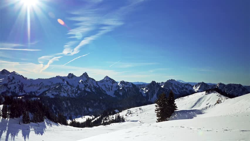 A sun-drenched winter landscape captures the snow-covered peaks of Mount Rainier National Park, Washington State, as seen from the popular Skyline Trail heading towards Panorama Point. The bright blue