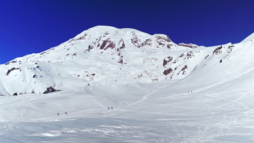 Footage of the majestic, snow-covered Mount Rainier as seen from the Skyline Trail in Mount Rainier National Park, Washington State, USA. The scene captures the beauty of the winter landscape with sev
