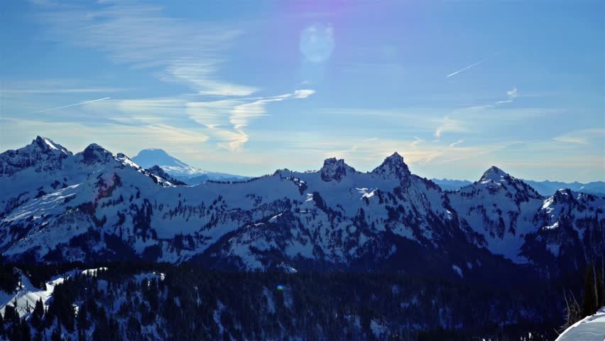A wide-angle shot of the snow-capped Mount Rainier volcano and the surrounding Tatoosh Range, as viewed from the popular Skyline Trail in the Paradise area of Mount Rainier National Park, Washington S