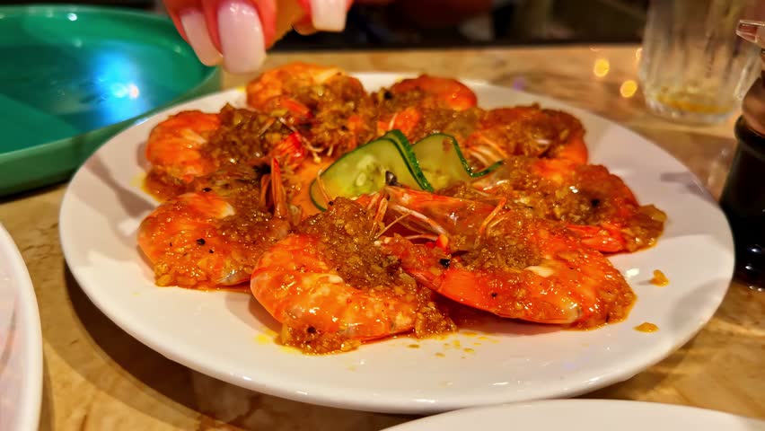 Person squeezing lemon on delicious seafood platter with shrimp and lobster