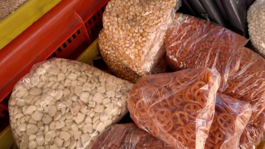 Closeup view of packaged beans lentils and pasta arranged inside plastic bags at traditional local market with dry food products and colorful display
