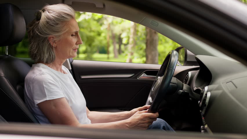 Stressful suffering tired Caucasian old elderly aged senior woman lying leaning on steering wheel in car suffer stress problem depressed retired female in auto feeling headache head pain in automobile