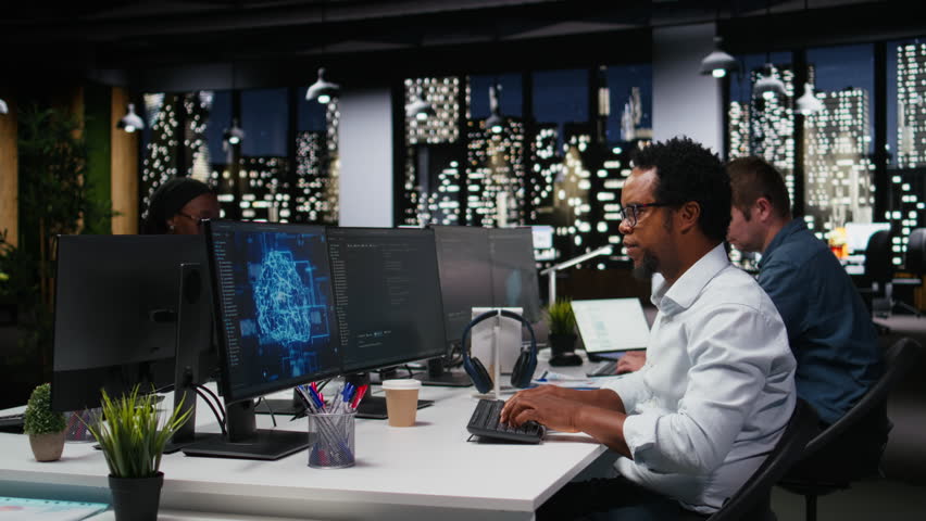 Tech startup IT specialist developing AI algorithms in high-rise office, listening music, while an admin wears headphones and debugs neural network brain models on screens.
