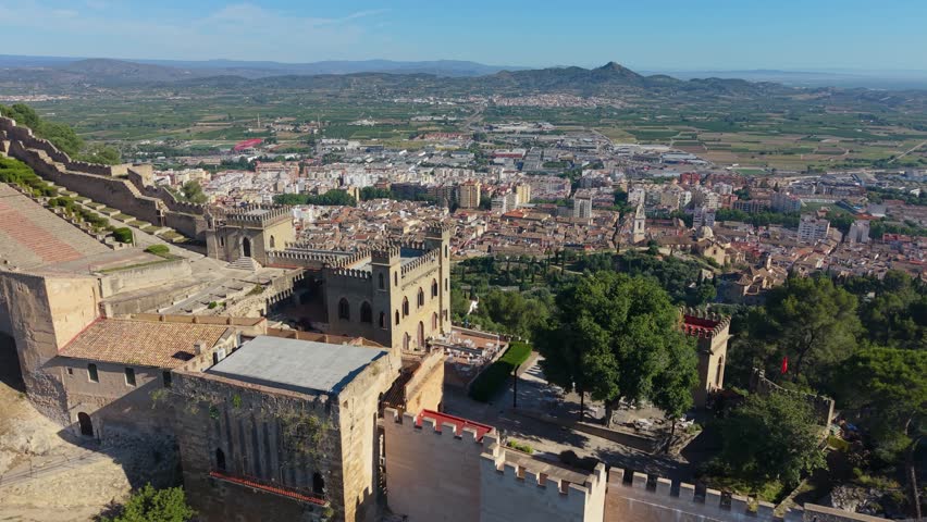 Drone aerial view from Xàtiva Castle overlooking the historic city of Xàtiva, Spain with medieval fortifications, urban landscape, and fertile valley beyond