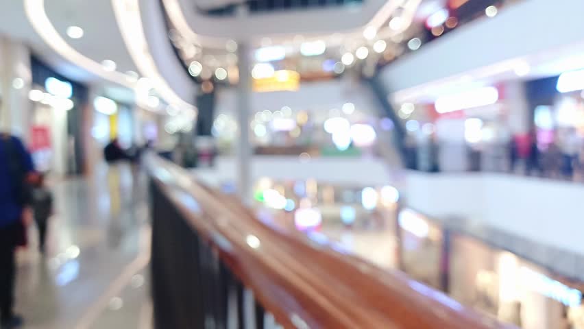 Blurred Background of a Modern Shopping Mall Interior with Bright Bokeh Lights and People Walking