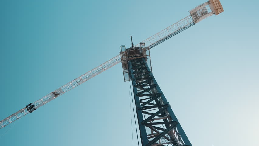 Tower crane mast and jib against clear blue sky