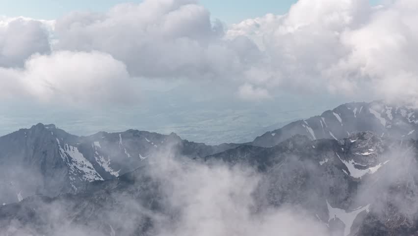 Misty clouds over Swiss Alps highlands mountain peak high altitude aerial drone Switzerland