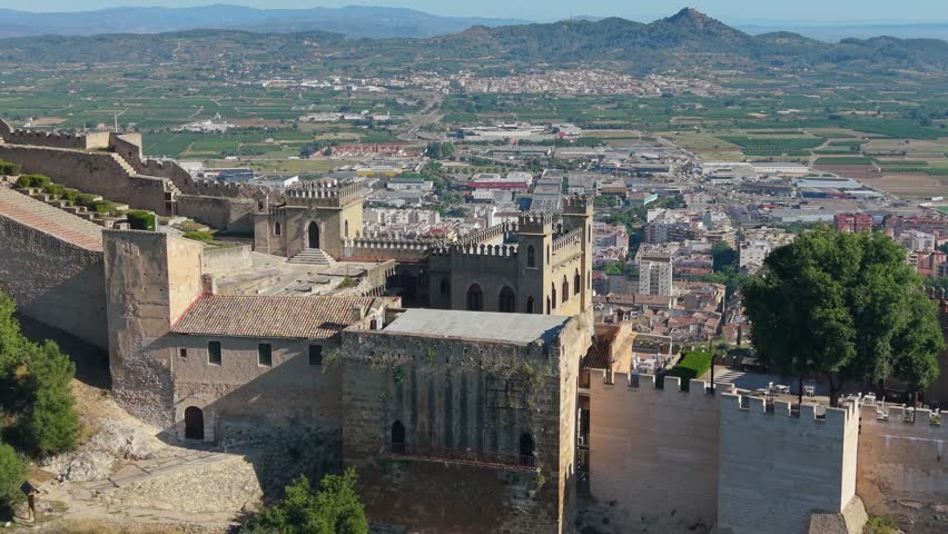 Drone aerial view of the fortified buildings and defensive walls of Xàtiva Castle overlooking the city of Xàtiva, Spain and the surrounding Valencian valley