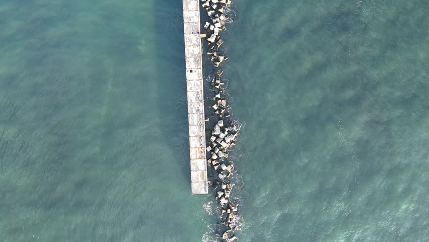 Top down drone shot over seawall tilting up toward Lange Anna and Helgoland cliffs.